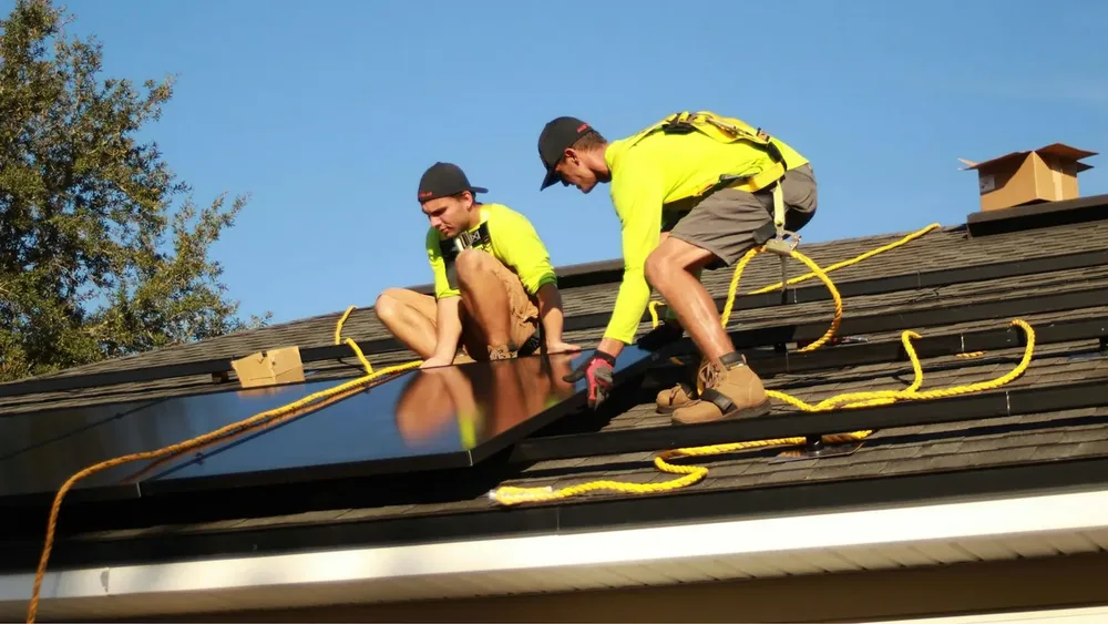 Technicians mounting solar panels on a roof
